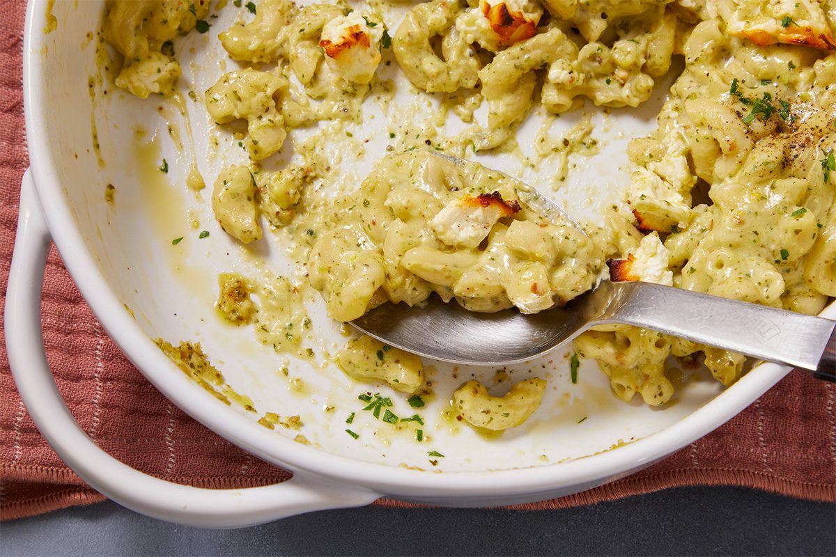 Eye Level horizontal image of mac and cheese. A spoonful of mac and cheese is being lifted from the baking dish.