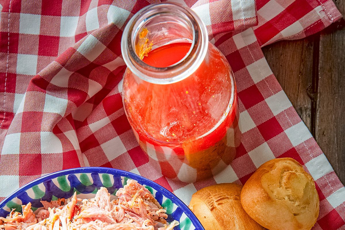 top view of West North Carolina Bbq Sauce with pulled pork on a checkered red cloth
