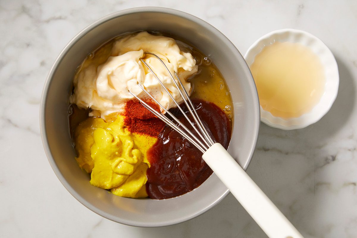 Dijon mustard being mixed with barbecue sauce and honey in a bowl