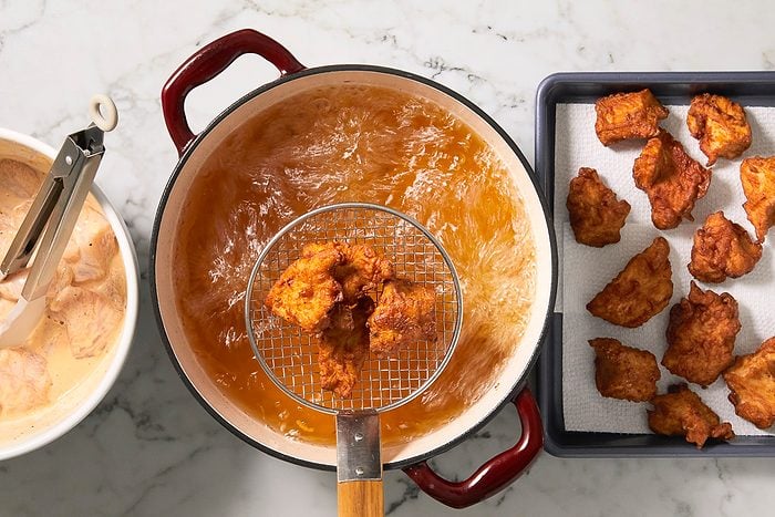 A horizontal overhead image shows breaded chicken nuggets frying in hot oil in a pot, with a slotted spoon lifting cooked pieces.