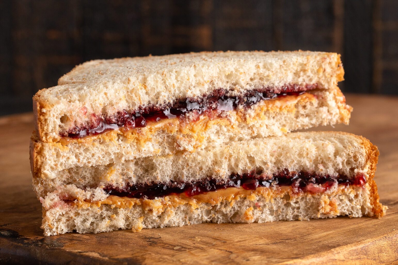 A Peanut Butter and Grape Jelly Sandwich on a Wooden Cutting Board