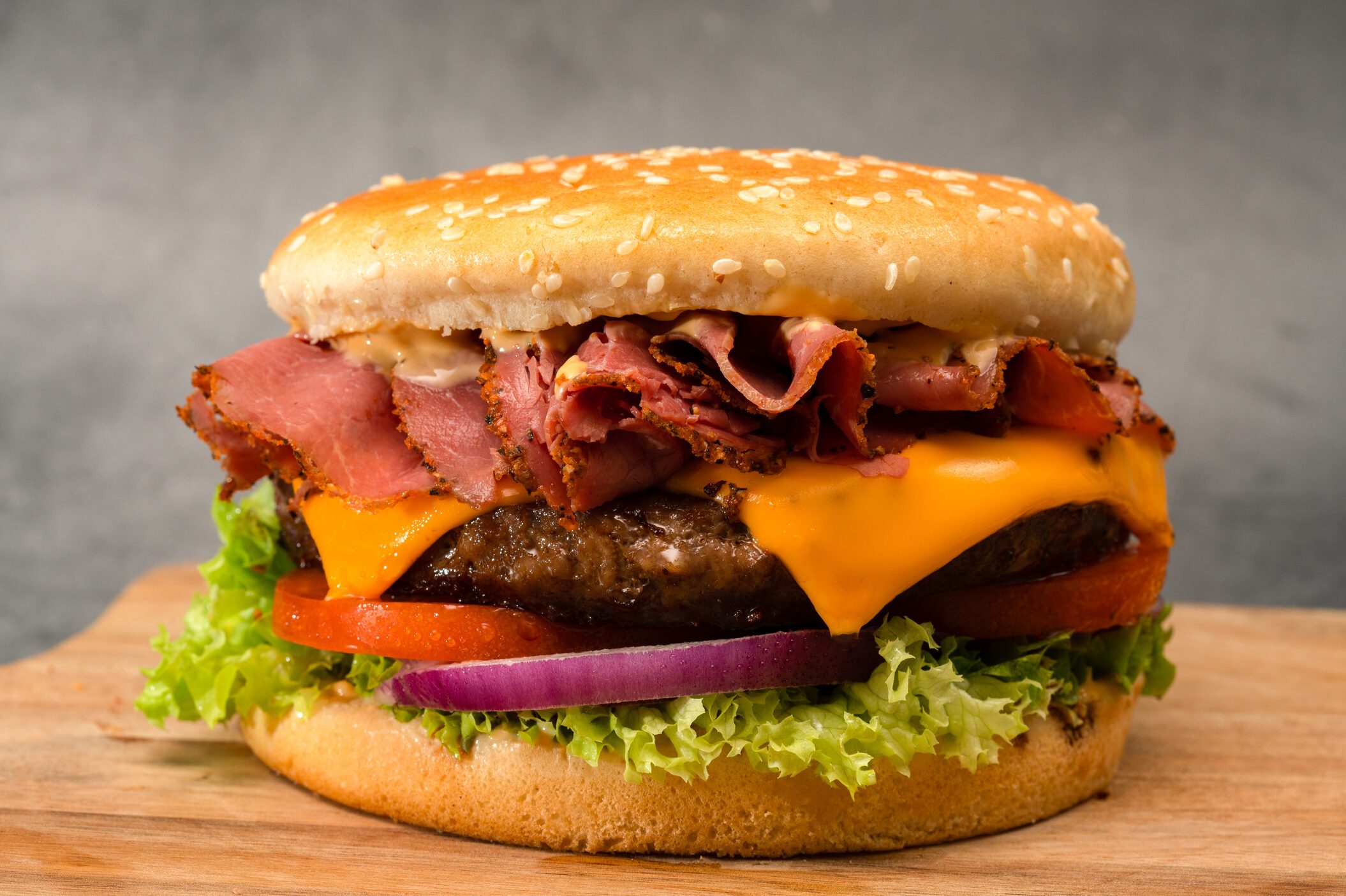 Delicious cheeseburger with tomatoes, onion, lettuce, pastrami and cheese