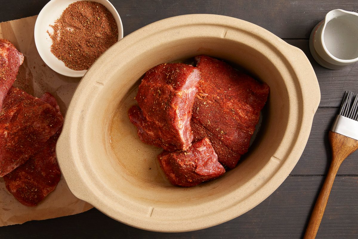 overhead view of seasoned pork ribs in a 6 quart slow cooker