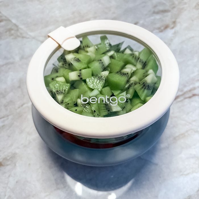 A round glass container with a white lid and clear window, labeled 