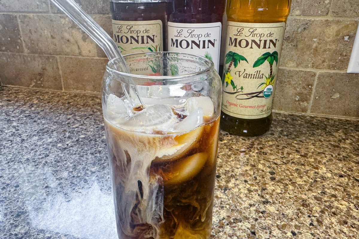cold beverage on a kitchen counter with bottles of syrup in the background