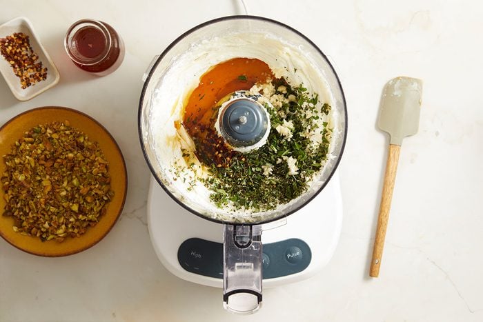 food processor placed on a counter, accompanied by several ingredients prepared for meal preparation.