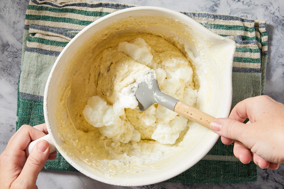 Overhead horizontal image of whipped egg whites folded into batter mixture for light texture.