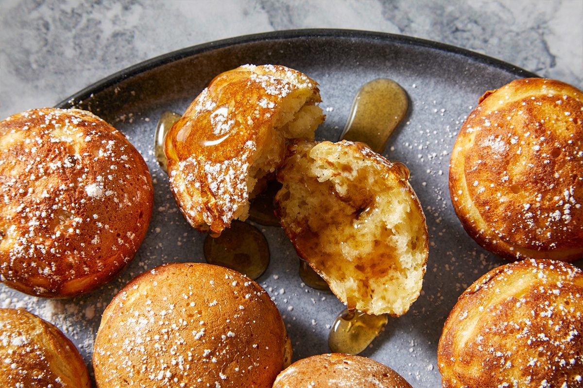 Eye-level horizontal close-up of aebleskivers showing golden exterior and fluffy interior with powdered sugar.