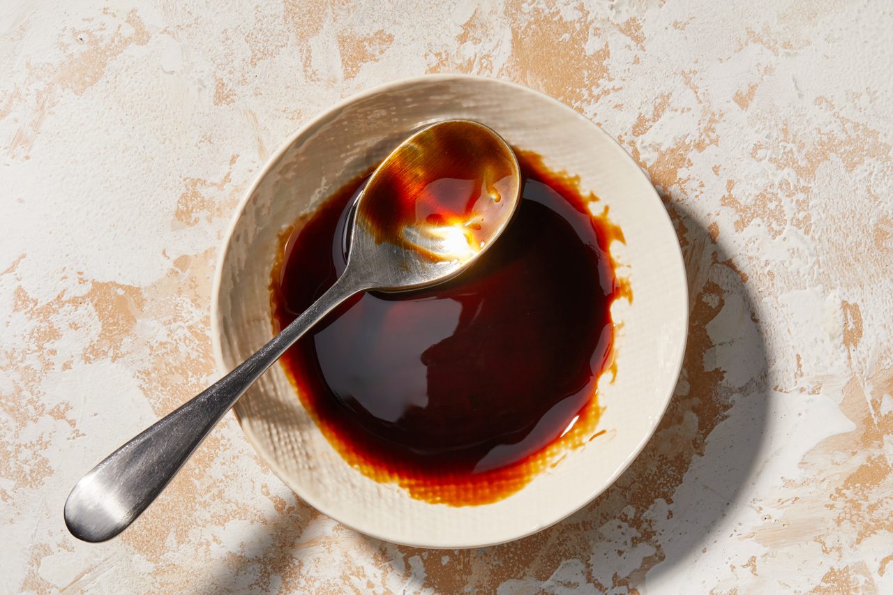 Overhead image of a bowl containing a dark brown liquid with a spoon in it.