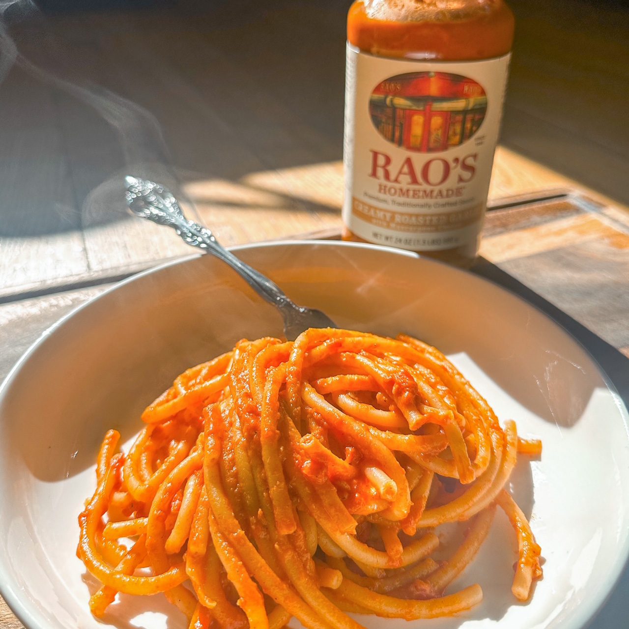 spaghetti on a plate in front of Rao's Creamy Roasted Garlic Sauce