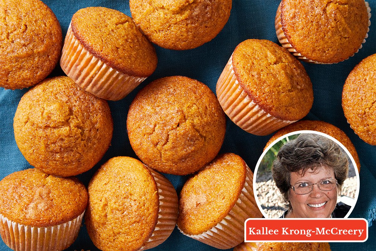 A group of golden-brown muffins on a blue cloth, with a small inset photo of a smiling woman and a name label in the bottom right corner.