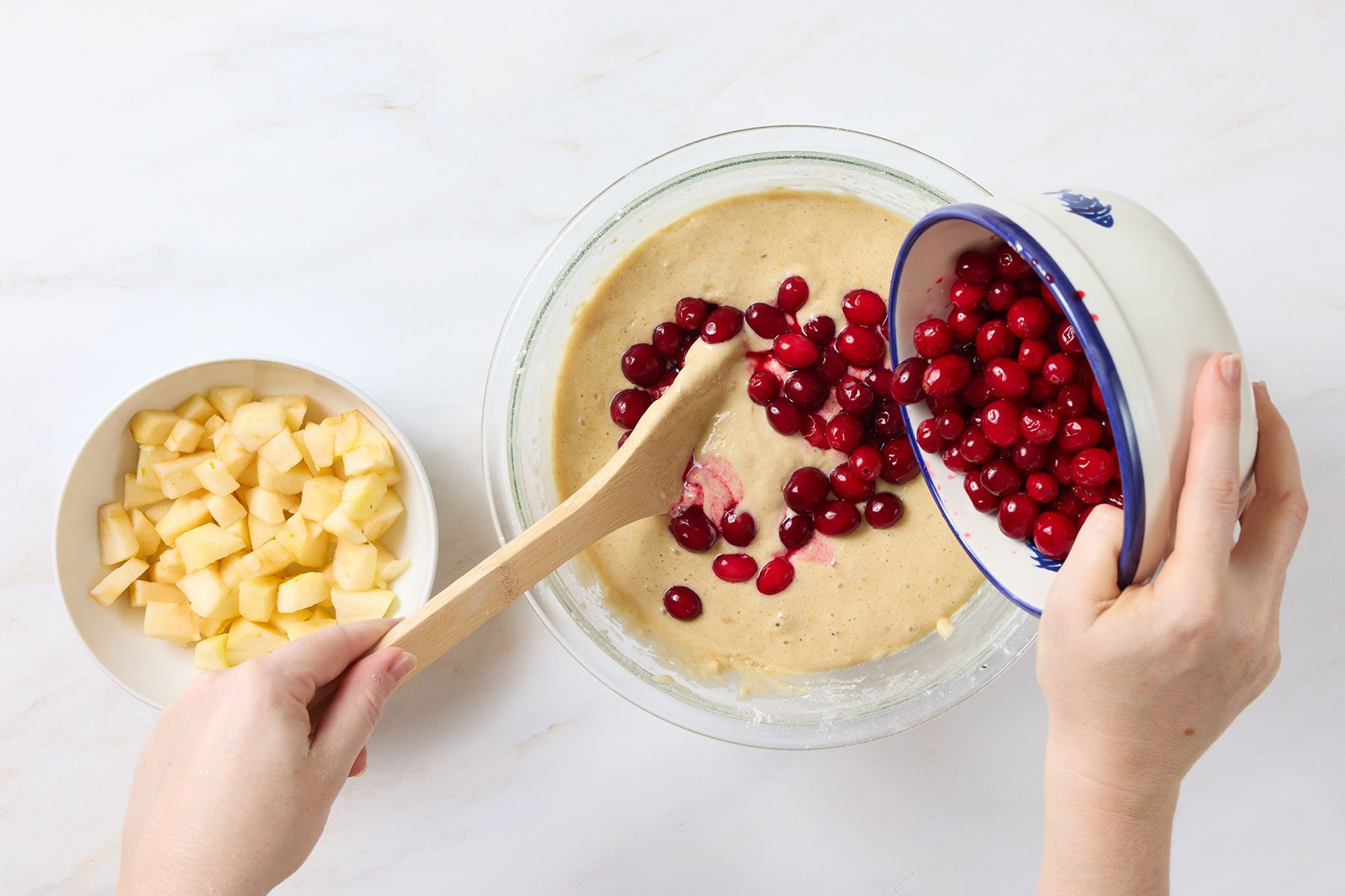 Gently folding in the chopped cranberries and apple until they're evenly distributed throughout the batter.