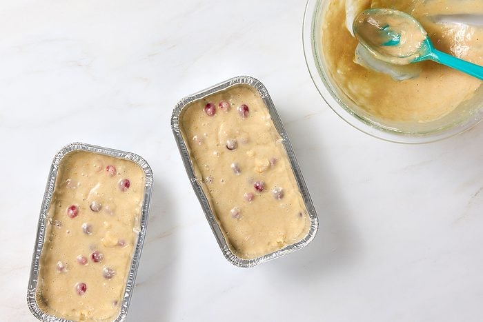 Cranberry orange bread batter poured into two greased 8x4-inch loaf pans.