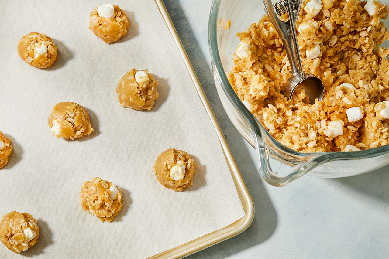 Overhead view of cookie dough portions scooped and spaced evenly on a parchment-lined baking sheet, preparing the cookies for baking.