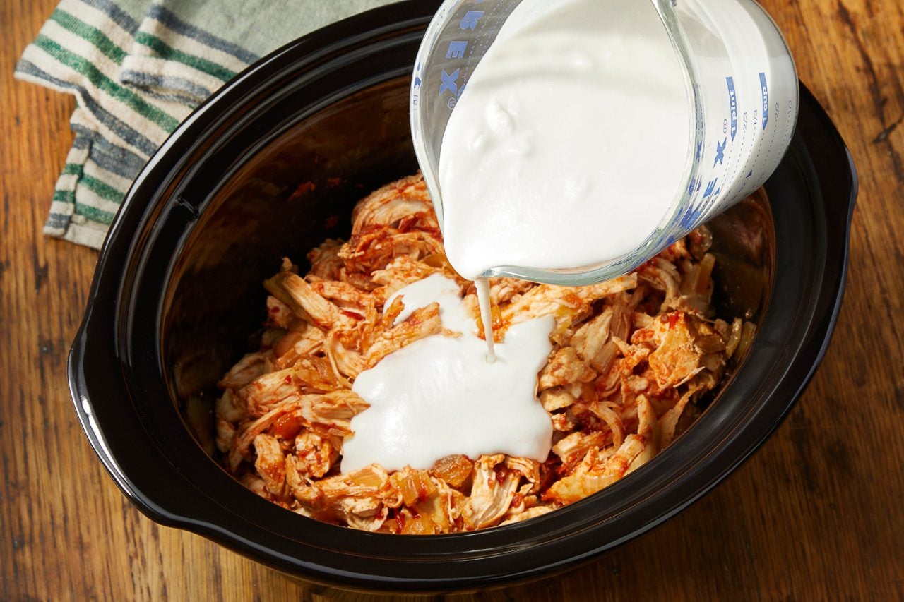 coconut milk and cornstarch mix sauce being added to shredded chicken
