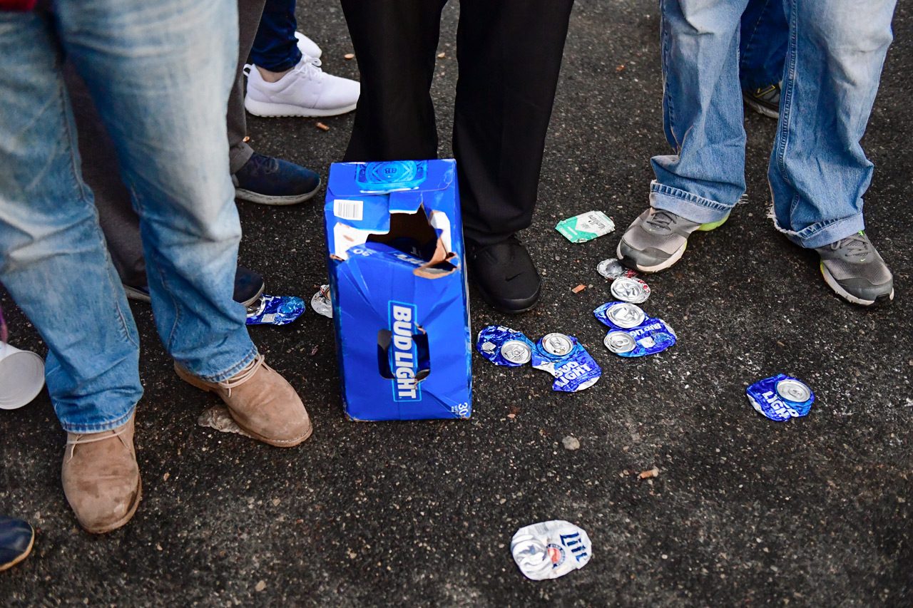 Beer cans are shown at the feet of patrons while tailgating