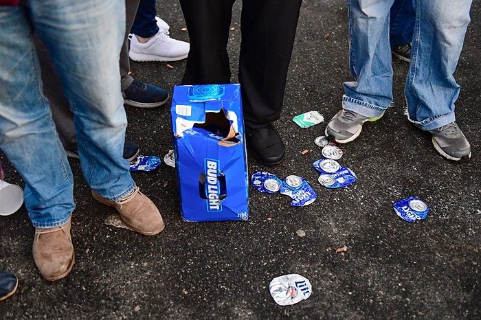 Beer cans are shown at the feet of patrons while tailgating