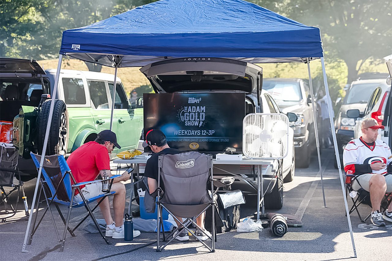 fans sitting in a tent while tailgating in a parking lot