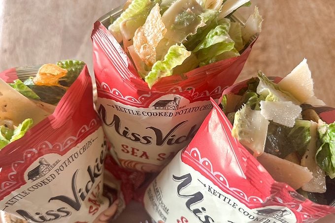 Three open red-and-white Miss Vickie’s Sea Salt kettle-cooked potato chip bags, filled with chips, lettuce, cheese, and salad ingredients.