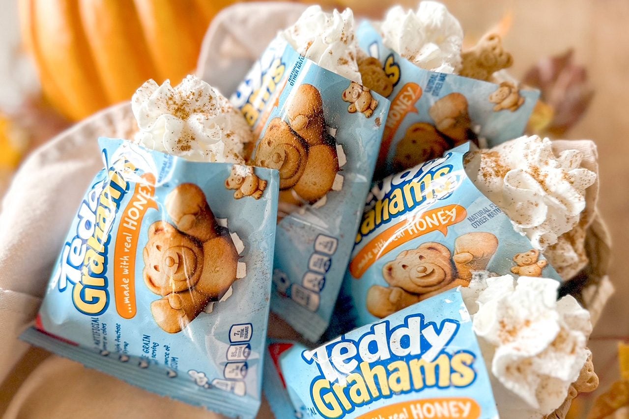 Colorful Teddy Grahams Honey snack packs nestled among fluffy popcorn, featuring smiling teddy bear graphics in a warm, playful display.