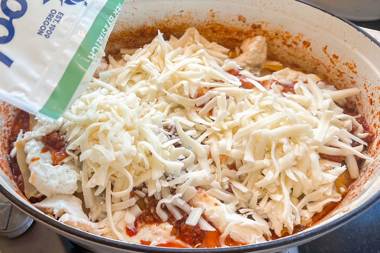 A close-up of a casserole dish filled with tomato sauce, ricotta, and shredded mozzarella cheese.